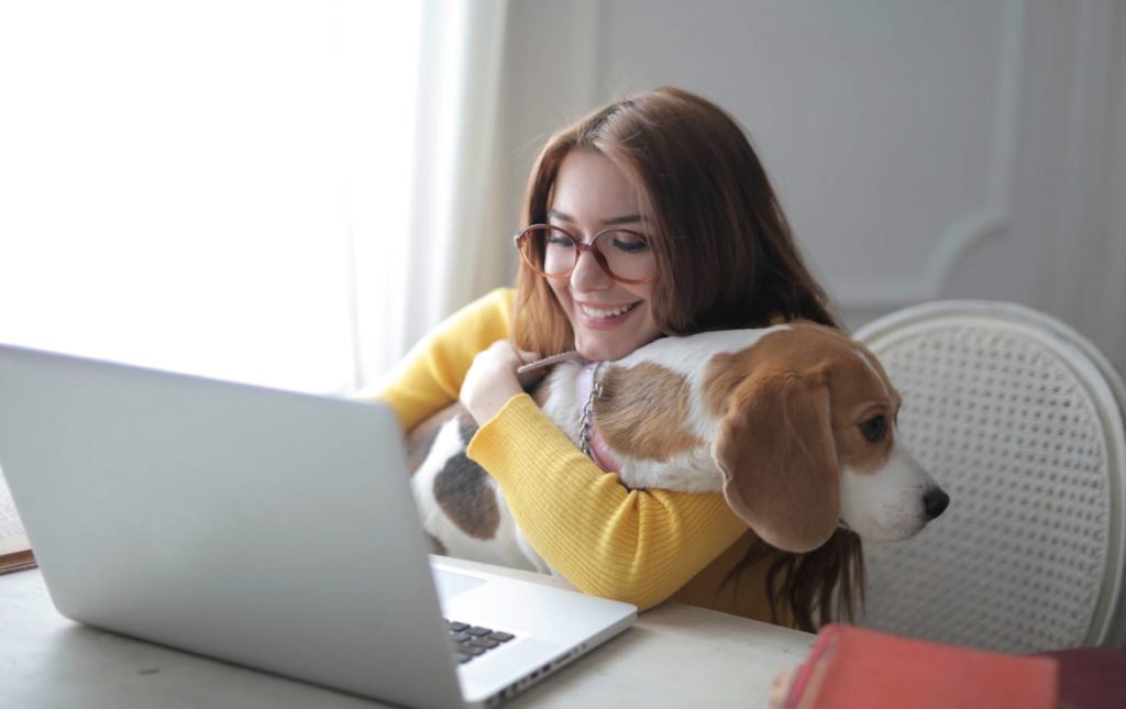 Woman working from home with her dog on her lap.